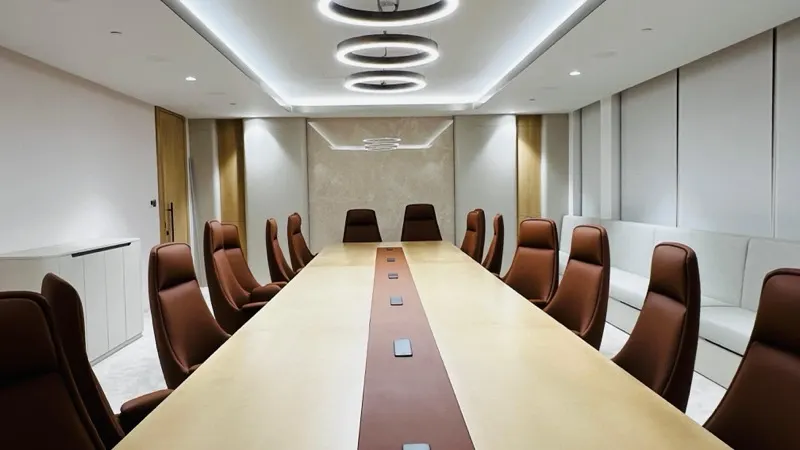 Boardroom with a long table and a full-height crema marble end wall