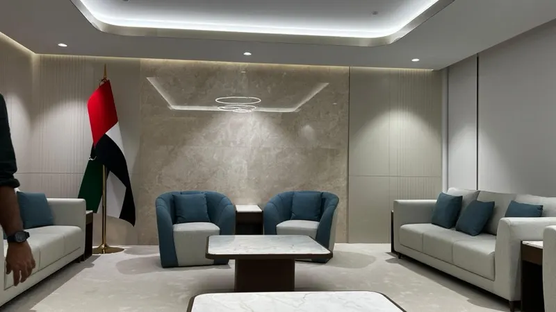 Majlis seating area in front of a crema marble feature wall with the UAE flag