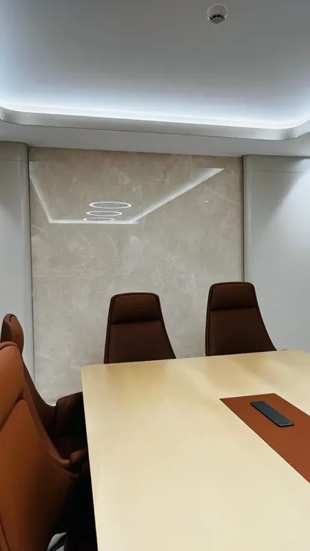 Marble feature wall with a lit ceiling recess behind a meeting table